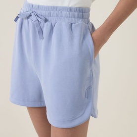 Model wearing light blue drawstring waist sweat shorts with tonal embroidered detail and side pockets, styled with a white top