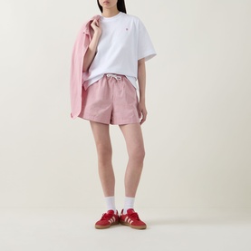 Model wearing Sweaty Betty Pink White Stripe shorts with white tee, pink shirt and red trainers