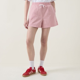 Model wearing Sweaty Betty shorts in pink white stripe with white drawstring waist, styled with white ankle socks and red trainers