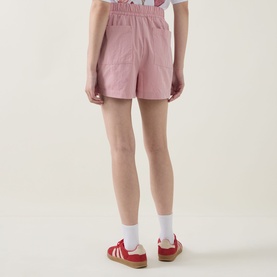 Model wearing Sweaty Betty Pink White Stripe shorts, rear view, styled with white socks and red Adidas trainers.