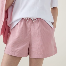 Model wearing Sweaty Betty shorts in pink white stripe, with drawstring waist, styled with white tee and pink shirt