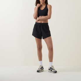Model wearing black loose-fit shorts with black sports bra, white ankle socks and grey chunky trainers