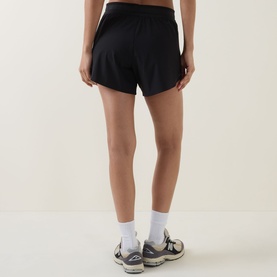 Model wearing black athletic shorts, styled with white ankle socks and grey trainers, rear view