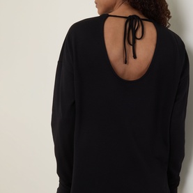 Model wearing Sweaty Betty After Class Open Back Tie Sweatshirt in black, shown from behind highlighting the open back with tie detail.