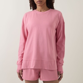 Model wearing pink crew neck sweatshirt with matching pink shorts, long sleeves and relaxed fit