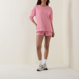Model wearing pink oversized sweatshirt and matching shorts set with white socks and chunky trainers