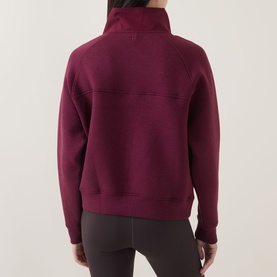 Model wearing Sweaty Betty Wind Down Textured Half-Zip Sweatshirt in Merlot Red, back view, with dark grey leggings.