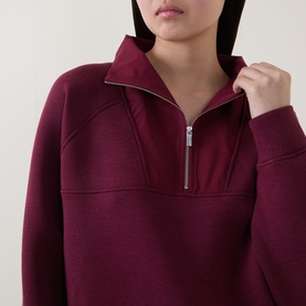 Model wearing Sweaty Betty Wind Down Textured Half-Zip Sweatshirt in Merlot Red, close-up of zip collar detail