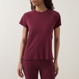 Model wearing Sweaty Betty Merlot Red T-shirt with raglan sleeves, styled with matching wide-leg trousers.