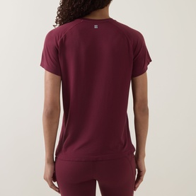 Model wearing Sweaty Betty Merlot Red T-shirt, back view, paired with matching Merlot Red leggings.