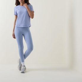 Model wearing Sweaty Betty Laguna Blue T-shirt, styled with matching blue leggings and grey trainers