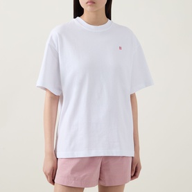 Model wearing Sweaty Betty Holiday Graphic T-Shirt in Red Equipment Print, styled with matching pink shorts, oversized fit, button-front detail.