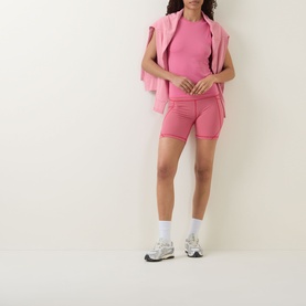 Model wearing Sweaty Betty Crimson Red Drop Needle Stripe tank, styled with matching pink cycling shorts and zip-up hoodie tied over shoulders