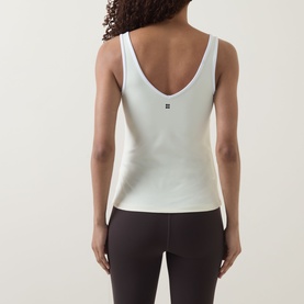 Model wearing Sweaty Betty tank in Butterscotch Yellow, back view, with small logo detail, styled with dark leggings.