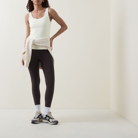 Model wearing Sweaty Betty tank in Butterscotch Yellow, styled with dark leggings, white socks and chunky trainers