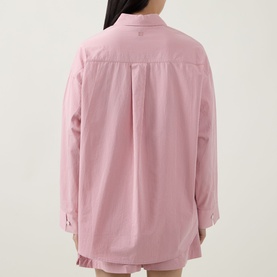 Model wearing Sweaty Betty Summer Stripe Shirt in Pink White Stripe, back view showing branded graphic print, styled with pink shorts.