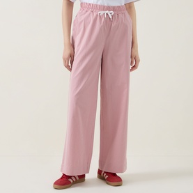 Model wearing pink wide-leg drawstring trousers with elasticated waist, styled with red trainers