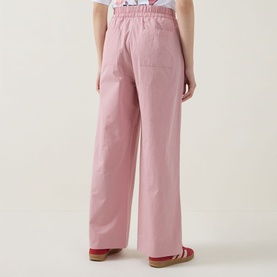 Model wearing pink wide-leg trousers with elasticated waist, styled with a white top and pink flat sandals, rear view.