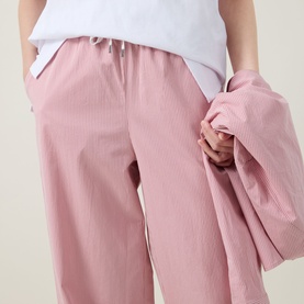 Model wearing pink wide-leg textured trousers with elasticated drawstring waist, styled with matching pink jacket and white top