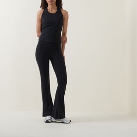 Model wearing Sweaty Betty black tank top, styled with matching black flared leggings and silver trainers