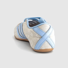 Adidas trainer in Chalk Pearl and Crystal Sky, rear view showing cross-strap detail, light blue overlays, and tan rubber sole.