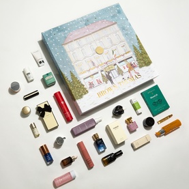 Brown Thomas Beauty Advent Calendar with illustrated boutique lid, surrounded by 25 miniature beauty products including skincare, fragrance and