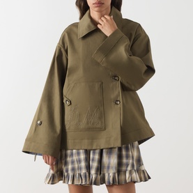 Model wearing Damson Madder olive cotton jacket with wide sleeves and patch pockets, styled with a plaid mini skirt.