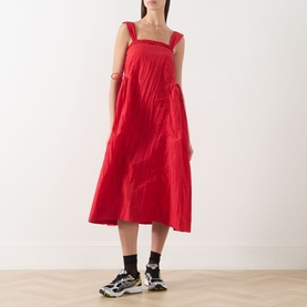 Model wearing Damson Madder red sleeveless midi dress with square neckline and wide straps, styled with black socks and chunky trainers.