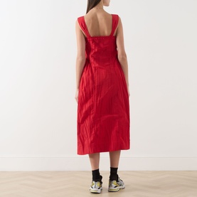 Model wearing Damson Madder red sleeveless midi dress with wide straps and open back, styled with black socks and chunky trainers.