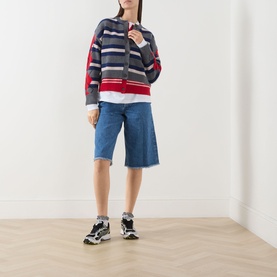 Model wearing Damson Madder Didi Layered Striped Cardigan in Argyle/Stripe with blue denim shorts and black trainers.