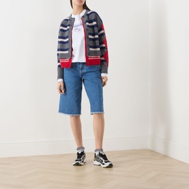Model wearing Damson Madder Didi Layered Striped Cardigan in Argyle/Stripe with blue denim shorts and chunky trainers.
