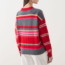 Model wearing Damson Madder pink/red stripe merino wool jumper, back view, with white wide-leg trousers