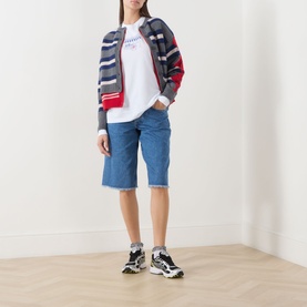 Model wearing Damson Madder white cotton T-shirt, styled with striped zip-up cardigan, blue denim shorts and chunky trainers.