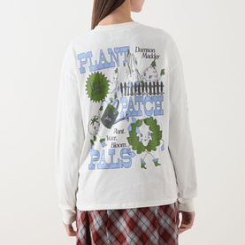 Model wearing Damson Madder Plant Patch Pals T-Shirt in white, long sleeves, Plant Patch Pals graphic print on back, styled with plaid trousers.