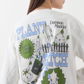 Model wearing Damson Madder Plant Patch Pals T-Shirt in white, showing back graphic with plant and fence illustration print, long sleeves with ribbed