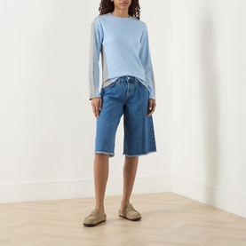 Model wearing Damson Madder blue cotton long-sleeve T-shirt, styled with mid-blue denim bermuda shorts and taupe loafers.