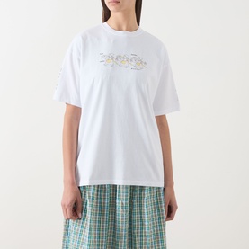 Model wearing Damson Madder white cotton T-shirt with gold script graphic, styled with green check midi skirt.