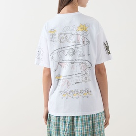 Model wearing Damson Madder white cotton T-shirt, back view with illustrated chameleon and nature graphic print, styled with green check trousers.