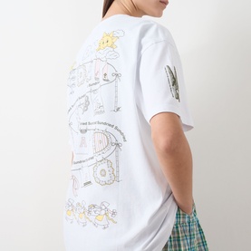 Model wearing Damson Madder white cotton T-shirt, back view showing colourful illustrated graphic print, styled with green checked skirt.