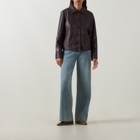 Model wearing Elena Miro Light Blue Wide-Leg Jeans, high-rise with tobacco stitching, styled with a dark brown leather jacket and brown shoes.