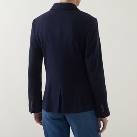 Model wearing Gant Single-Breasted Piqu&eacute; Blazer in blue, rear view showing vent, buttoned cuffs, styled with light blue jeans.