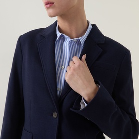 Model wearing Gant Single-Breasted Piqu&eacute; Blazer in blue with notched lapels, styled with a blue striped shirt underneath.