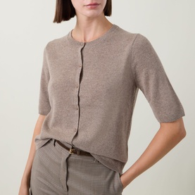 Model wearing Gant Brushed Knitted Cardigan in Sand, crew neck, short sleeves, button front, styled with checked mini skirt