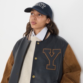 Model with Gant Graphic Logo Baseball Cap in navy, styled with a dark varsity jacket and cream knitwear