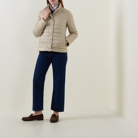 Model wearing Gant Light Logo Down Jacket in beige with navy wide-leg jeans and brown suede loafers