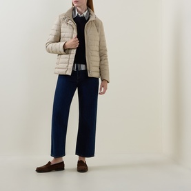 Model wearing Gant Light Logo Down Jacket in beige, styled with navy trousers, checked shirt and dark loafers