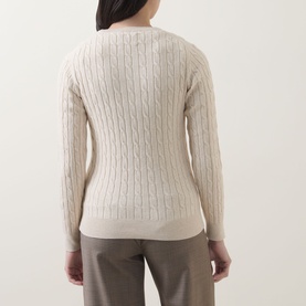 Model wearing Gant Shield Logo Cable Knit Sweater in beige, rear view showing cable knit pattern and ribbed hem, styled with taupe trousers.