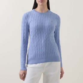 Model wearing Gant Shield Logo Cable Knit Sweater in lavender, crew neck, long sleeves, cable knit texture, styled with white trousers.