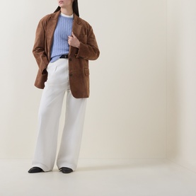 Model wearing Gant Shield Logo Cable Knit Sweater in Lavender, styled with brown blazer, white wide-leg trousers and black loafers.