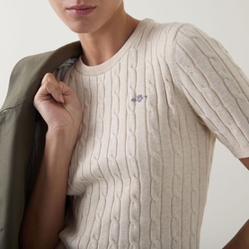 Model wearing Gant beige cable-knit cotton short-sleeve jumper with embroidered logo, styled with an olive gilet.